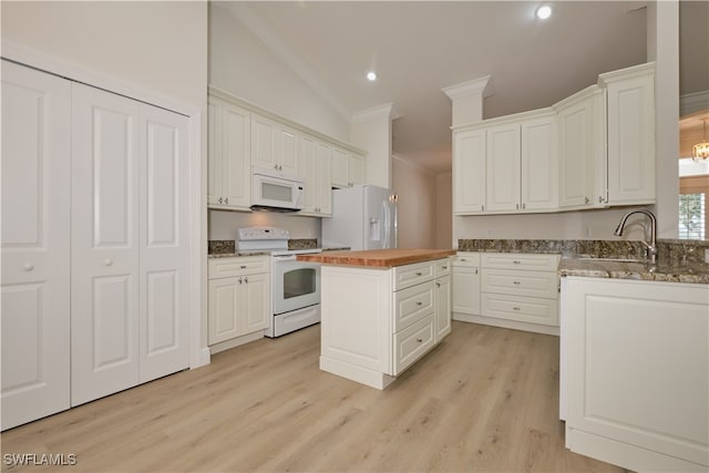 kitchen with white appliances, sink, butcher block countertops, white cabinetry, and vaulted ceiling