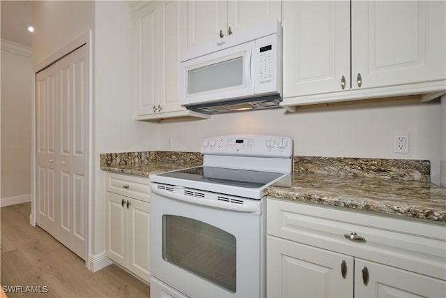 kitchen with white appliances, light hardwood / wood-style floors, dark stone counters, white cabinets, and ornamental molding