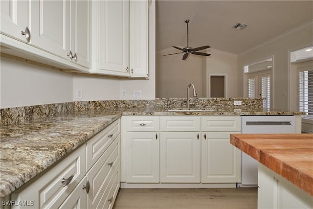 kitchen featuring white cabinets, vaulted ceiling, butcher block counters, crown molding, and sink