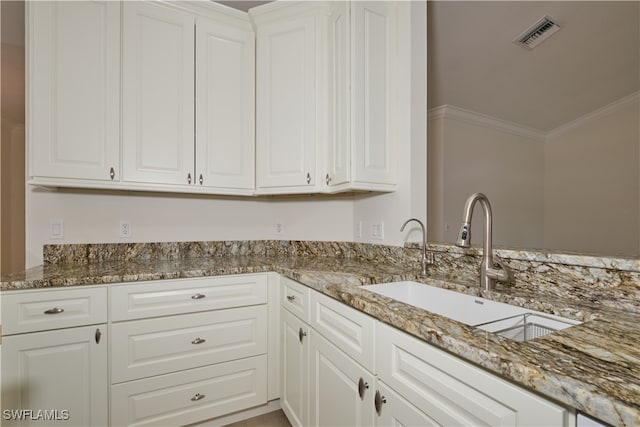 kitchen with stone counters, crown molding, and white cabinets