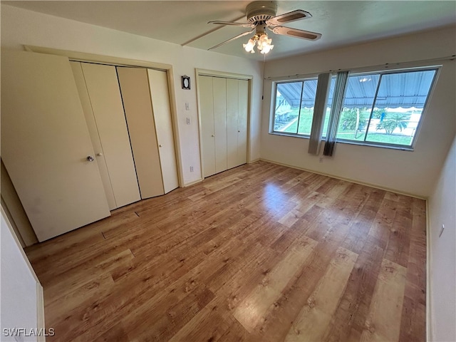 unfurnished bedroom with ceiling fan, multiple closets, and light hardwood / wood-style floors