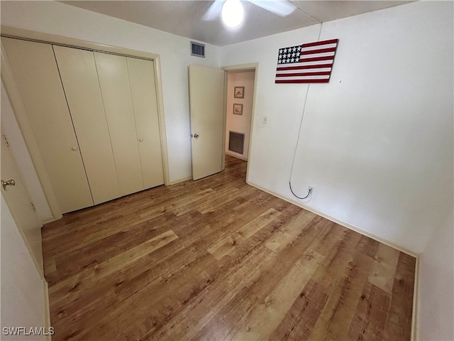 unfurnished bedroom with ceiling fan, hardwood / wood-style flooring, and a closet