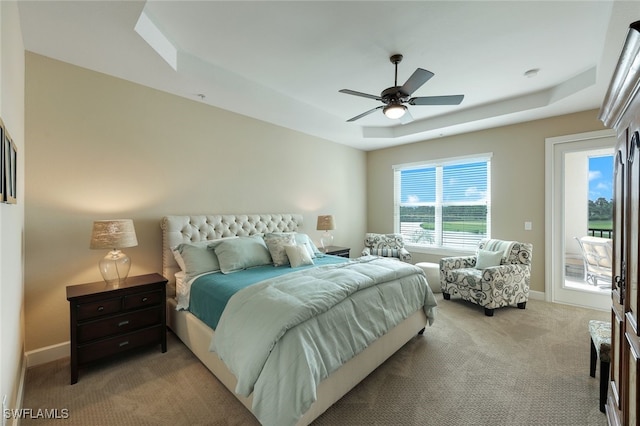 bedroom featuring a raised ceiling, light carpet, and ceiling fan