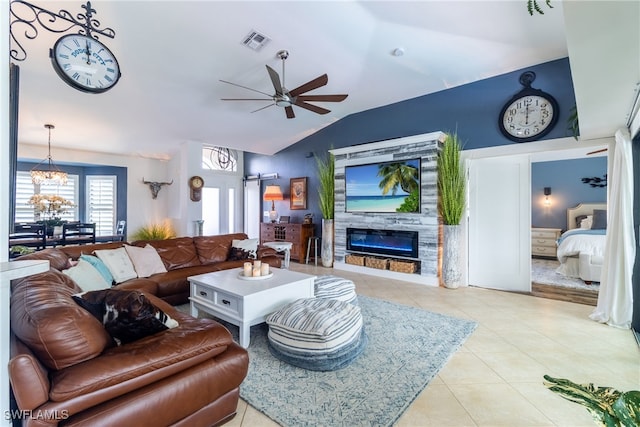 tiled living room with lofted ceiling, a fireplace, and ceiling fan with notable chandelier