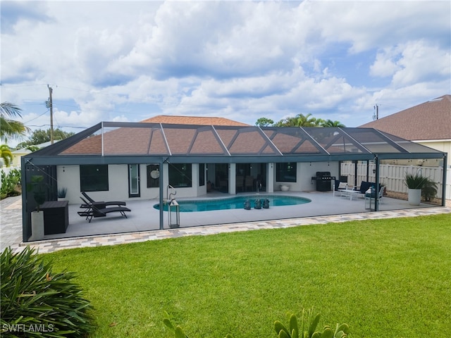 rear view of house featuring a patio, glass enclosure, and a lawn