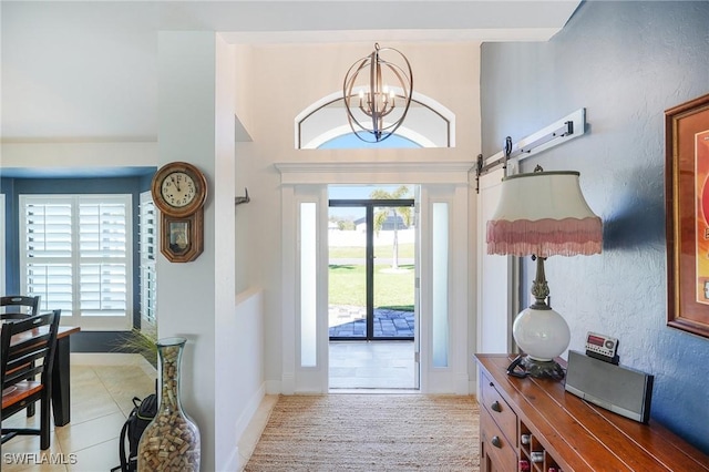 foyer entrance featuring a wealth of natural light, a notable chandelier, baseboards, and a barn door