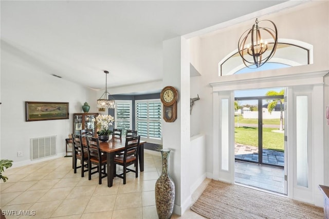 dining space featuring light tile patterned floors, visible vents, baseboards, lofted ceiling, and a chandelier