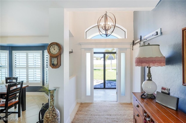 doorway with light tile patterned floors, plenty of natural light, a chandelier, and baseboards