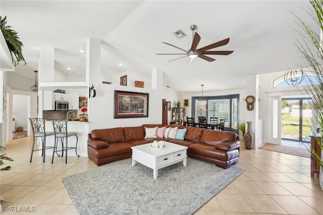 living area featuring light tile patterned floors, ceiling fan, visible vents, and high vaulted ceiling