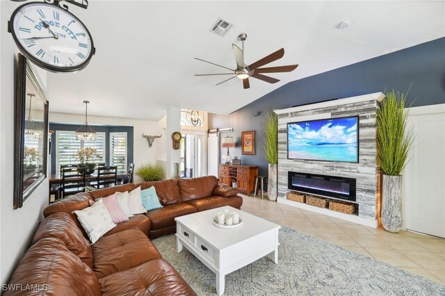 tiled living room featuring vaulted ceiling, a glass covered fireplace, visible vents, and a ceiling fan