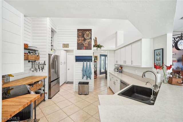 kitchen featuring light tile patterned floors, white cabinets, stainless steel appliances, light countertops, and a sink