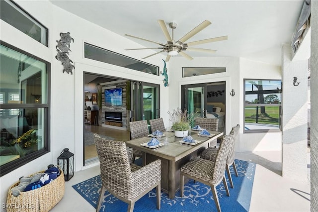 sunroom / solarium with ceiling fan, vaulted ceiling, and a glass covered fireplace