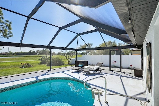 outdoor pool with a patio area, fence, glass enclosure, and a lawn