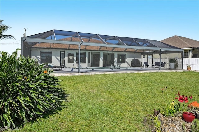 rear view of house with a lanai, a patio area, and a lawn