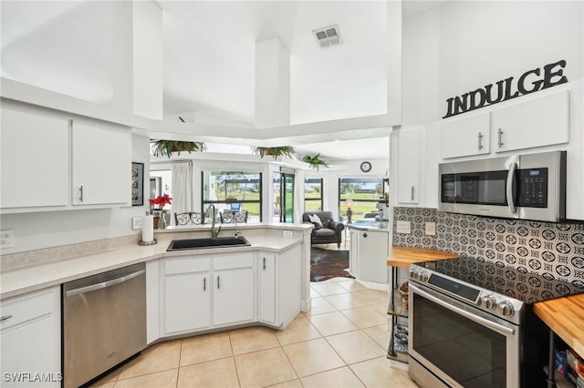 kitchen with stainless steel appliances, visible vents, light tile patterned flooring, a sink, and a peninsula