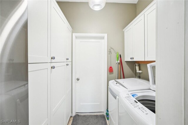 laundry area with separate washer and dryer and cabinet space