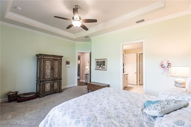 carpeted bedroom featuring a tray ceiling, ceiling fan, ensuite bathroom, and crown molding