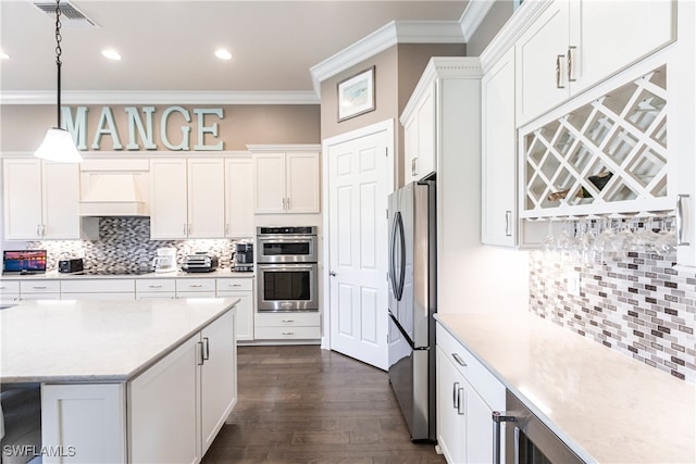 kitchen featuring dark hardwood / wood-style floors, custom exhaust hood, stainless steel appliances, decorative light fixtures, and ornamental molding