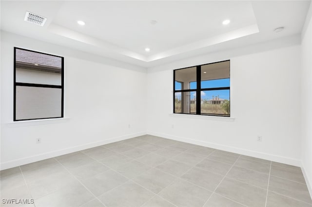 unfurnished room featuring a raised ceiling and light tile patterned floors