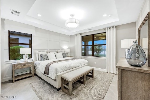 bedroom with light tile patterned flooring and a tray ceiling