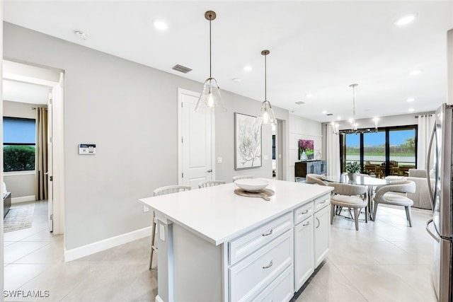 kitchen with stainless steel fridge, white cabinetry, a breakfast bar area, a center island, and decorative light fixtures