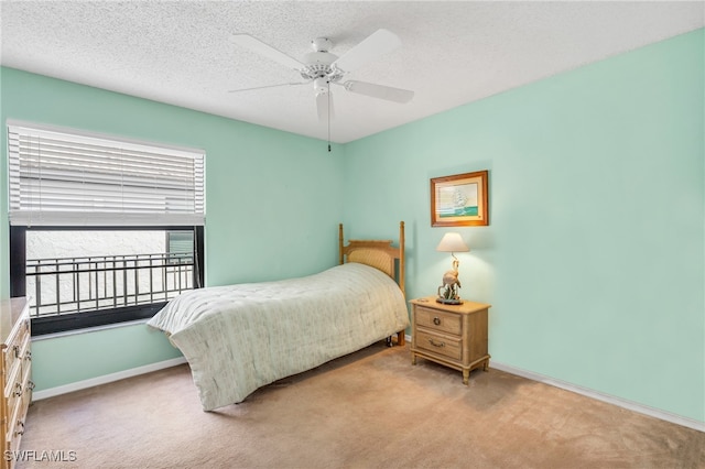 bedroom with ceiling fan, light colored carpet, and a textured ceiling