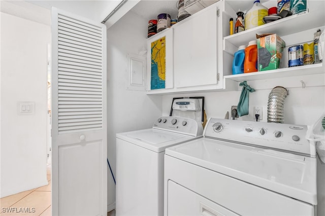 washroom with electric panel, separate washer and dryer, light tile patterned floors, and cabinets