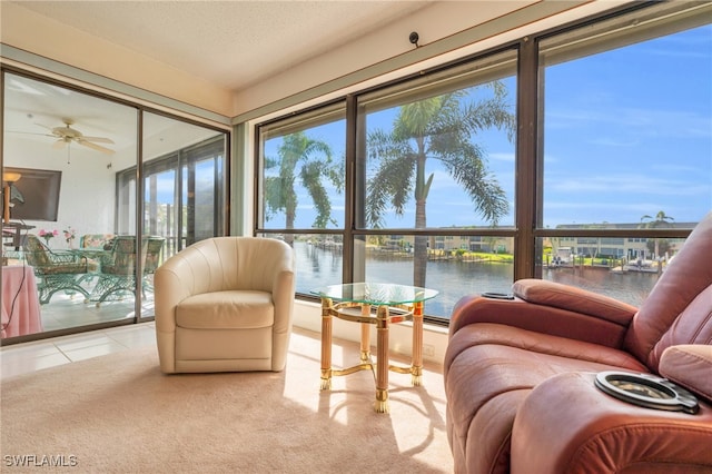 sunroom / solarium featuring a water view and ceiling fan