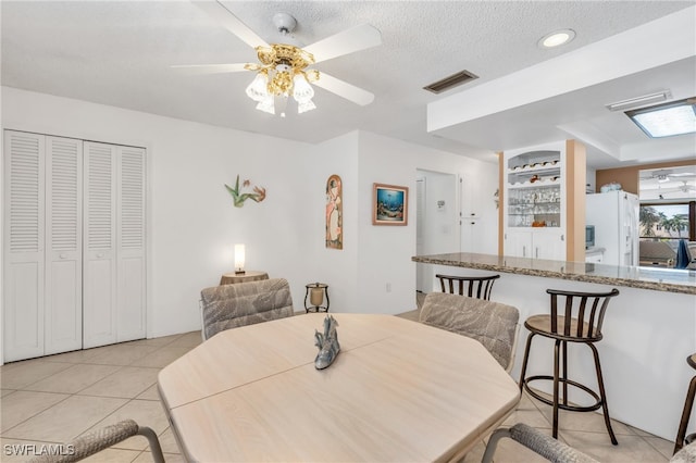 tiled dining space with ceiling fan and a textured ceiling