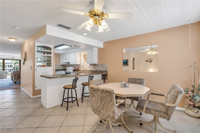 dining area featuring sink, light tile patterned floors, and ceiling fan