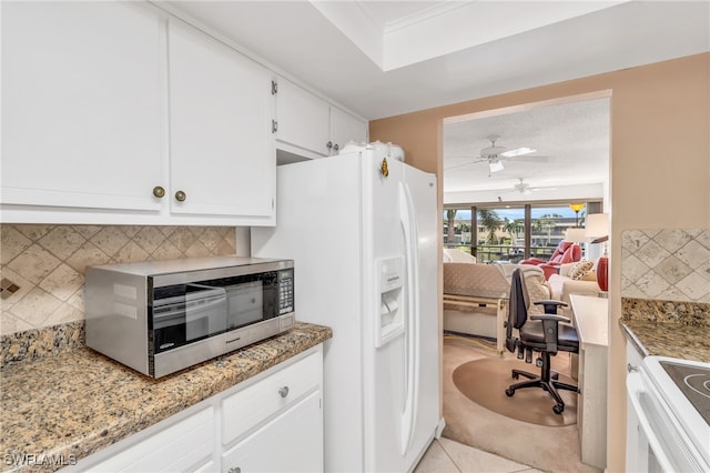 kitchen featuring light stone counters, white cabinets, light tile patterned floors, tasteful backsplash, and white appliances