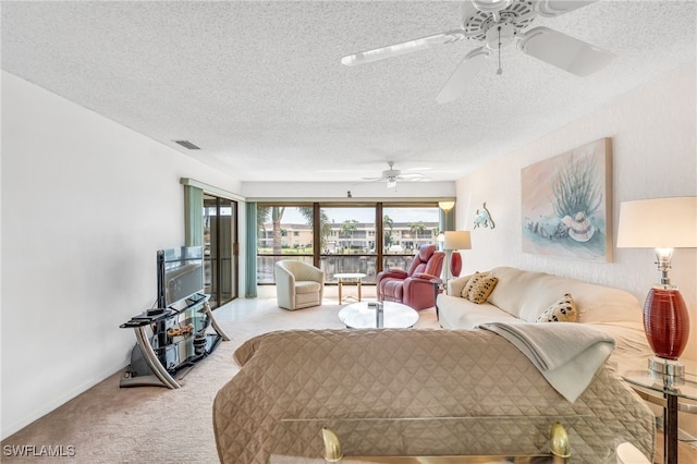 living room featuring light carpet, ceiling fan, and a textured ceiling