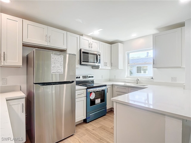 kitchen featuring stainless steel appliances, white cabinets, light hardwood / wood-style floors, and sink