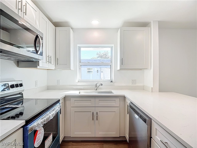 kitchen featuring white cabinets, sink, appliances with stainless steel finishes, light stone countertops, and dark hardwood / wood-style flooring