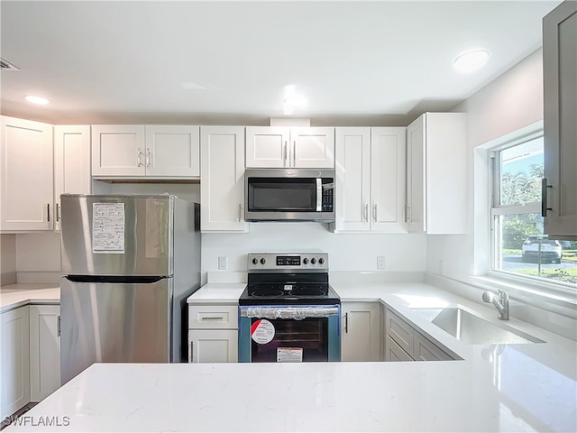 kitchen with appliances with stainless steel finishes, sink, and white cabinetry