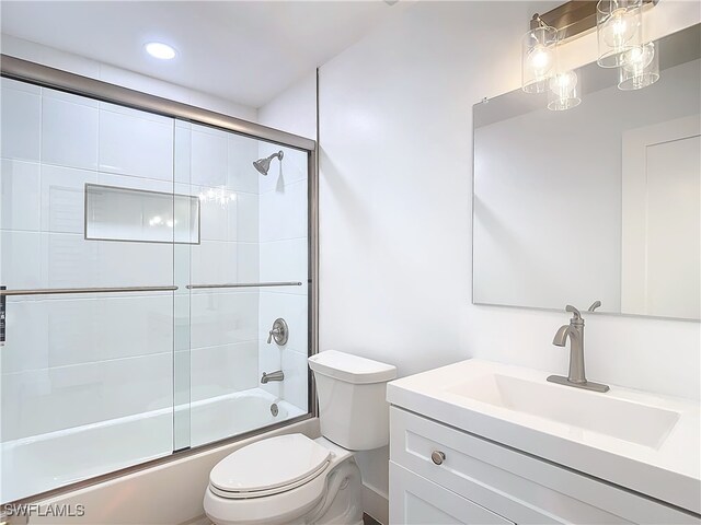 full bathroom with combined bath / shower with glass door, vanity, and toilet