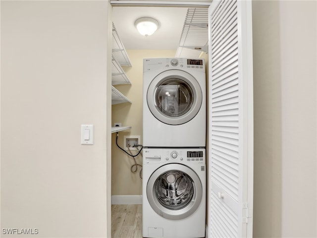 laundry room with stacked washer and clothes dryer and light hardwood / wood-style floors