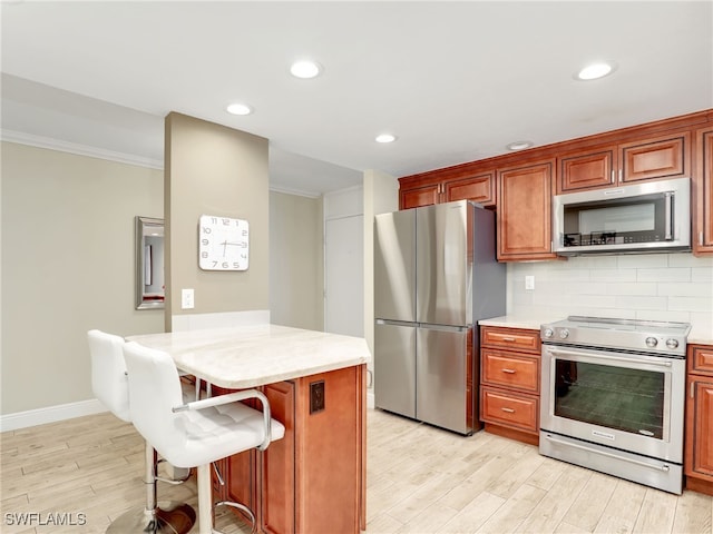 kitchen with a kitchen bar, light hardwood / wood-style flooring, stainless steel appliances, and tasteful backsplash