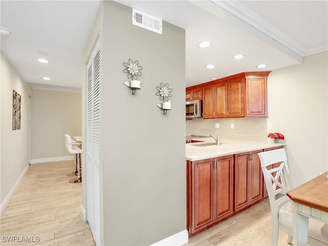 kitchen featuring light hardwood / wood-style flooring, crown molding, sink, and decorative backsplash