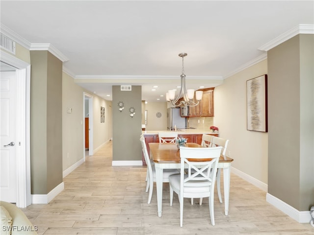 dining area with light wood-type flooring, ornamental molding, and a chandelier