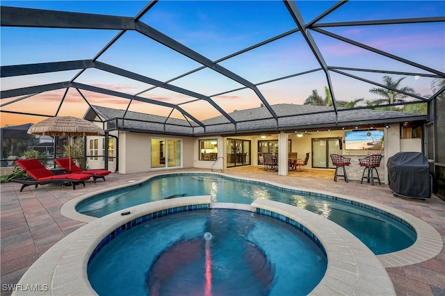 view of swimming pool with a lanai, a patio area, a pool with connected hot tub, and grilling area