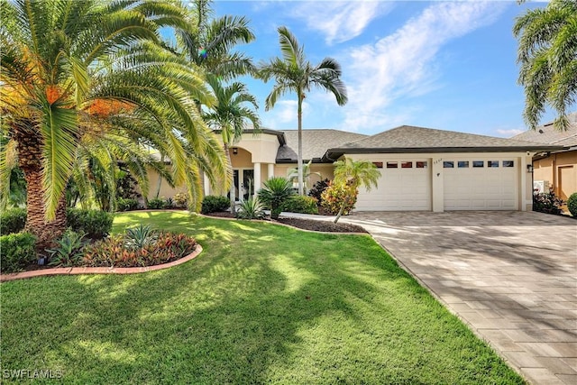 view of front facade with decorative driveway, an attached garage, a front yard, and stucco siding