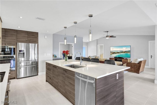 kitchen featuring appliances with stainless steel finishes, open floor plan, hanging light fixtures, light countertops, and a sink