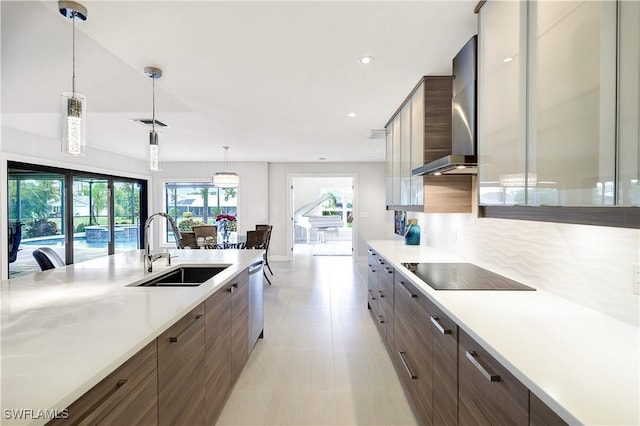 kitchen featuring wall chimney exhaust hood, modern cabinets, light countertops, and a sink