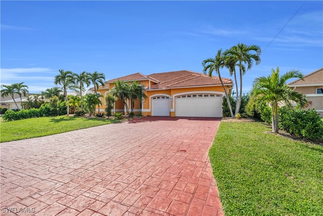 mediterranean / spanish house featuring a garage and a front yard