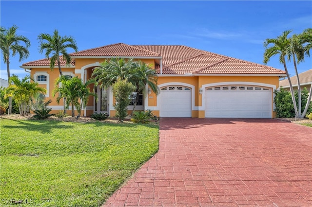 mediterranean / spanish-style home with a garage and a front lawn