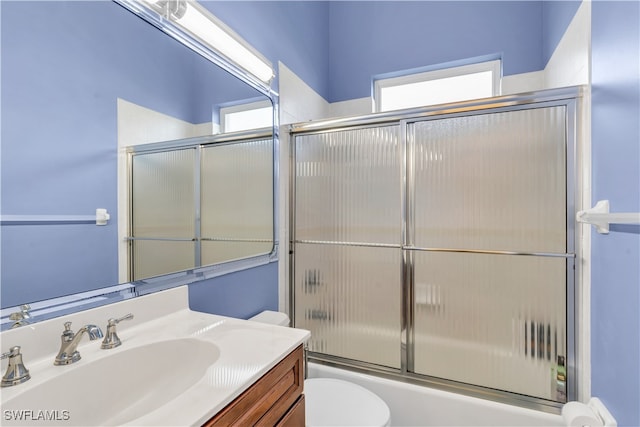 full bathroom with bath / shower combo with glass door, vanity, and toilet