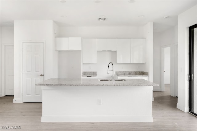 kitchen with white cabinetry, a center island with sink, light hardwood / wood-style floors, and sink