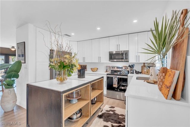 kitchen featuring white cabinets, stainless steel appliances, light wood-type flooring, and sink