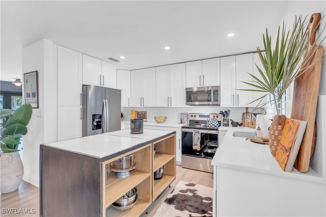 kitchen with light hardwood / wood-style floors, white cabinetry, sink, and stainless steel appliances